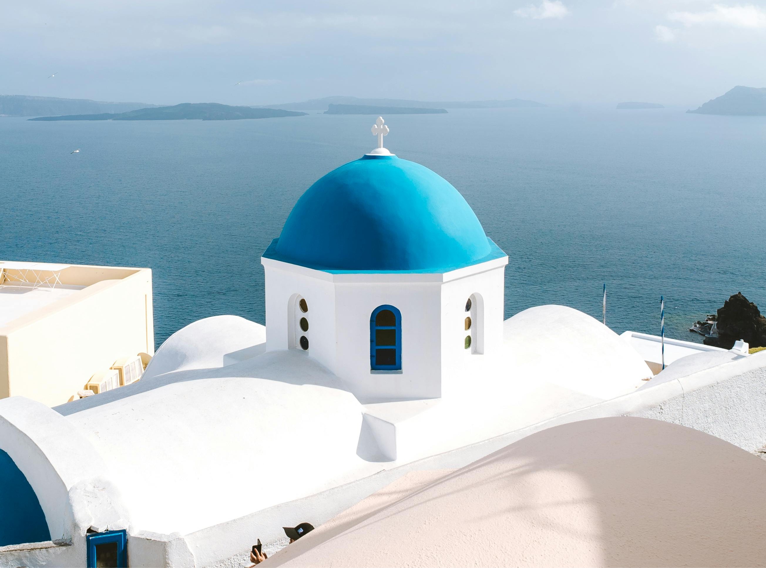 Blaue Kuppelkirche in Santorini mit Blick auf die Caldera – Inselhopping Griechenland