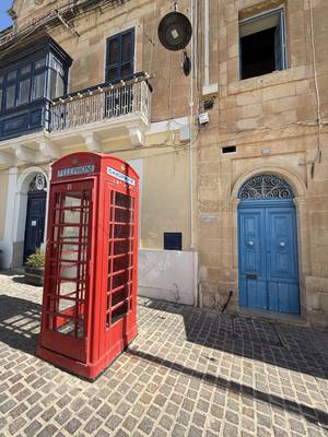 Rote Telefonzelle und blaue Tür in den Gassen von Marsaxlokk, Malta