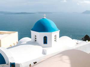 Blaue Kuppelkirche in Santorini mit Blick auf die Caldera - Inselhopping Griechenland
